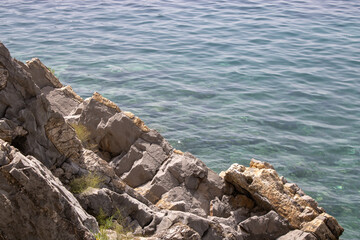 Big stone close-up on the background of the sea. Group of large gray stones. Boulders are standing in the beautiful water. Rocky seaside coast.