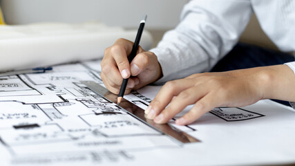 Engineer and Architect concept, Man uses a ruler to measure the floor plan on the blueprint,...