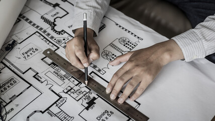 Engineer and Architect concept, Man uses a ruler to measure the floor plan on the blueprint,...