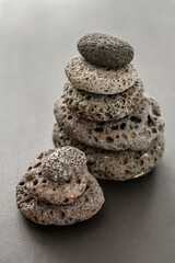 Pile of flat balanced round volcanic stones on grey background. Balanced pebbles, cairn or stack. Concept of stability, simplicity, harmony, balance, mindfulness, meditation, equilibrium and zen spa.