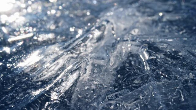 Sliding shot of real transparent ice. Camera moves over the ice of a frozen river or body of water. Climate change concept, ice melting