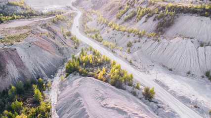 Dusty gravel road to the limestone quarry with heavy machinery.