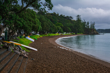 Colourful kayaks and dinghies lined up on an empty beach by the sea. Stormy day