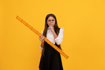 thinking teen girl in school uniform and glasses hold mathematics ruler for measuring, geometry