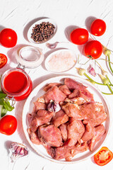Raw pork pieces, tomatoes, spices, and herbs