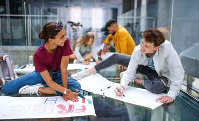University students activists making banners for protest indoors, fighting for free education concept.