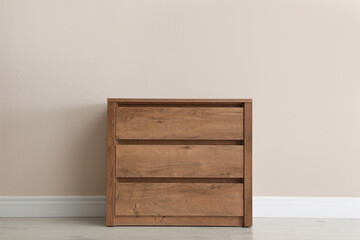 Wooden chest of drawers near beige wall