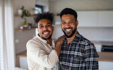Young adult brothers in kitchen indoors at home, looking at camera.