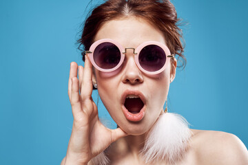 emotional woman wearing sunglasses fluffy earrings jewelry close-up blue background