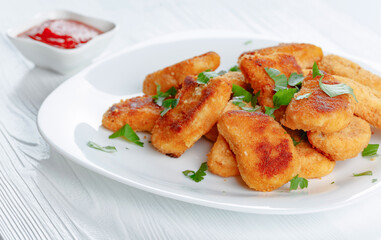 Fried chicken nuggets with ketchup sprinkled with chopped parsley.