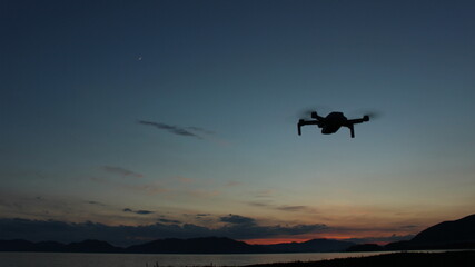 マジックアワーの瀬戸内海を飛行するドローンのシルエット