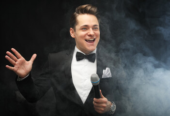 Stylish man in a tuxedo holding a microphone, actor, singer, show, host of the event.