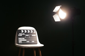 Chair with clapperboard under spotlight in studio