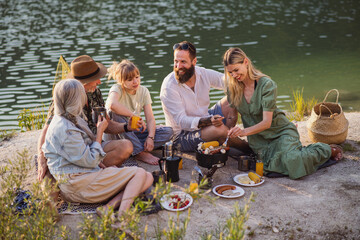 Happy multigeneration family on summer holiday trip, barbecue by lake.