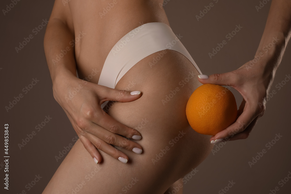 Poster Closeup view of slim woman in underwear with orange on beige background. Cellulite problem concept