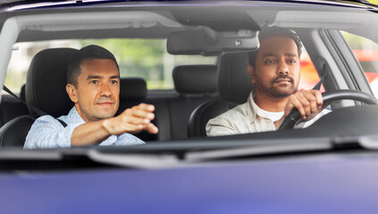 driver courses and people concept - car driving school instructor teaching young man to drive