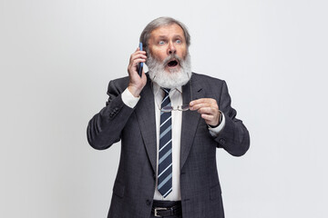 High angle view of elderly gray-headed man, professor, teacher posing isolated on gray studio background. Concept of professional occupation, job, education and motivation.