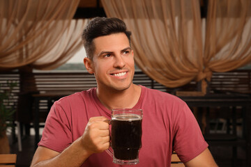 Man with glass of dark beer in outdoor cafe