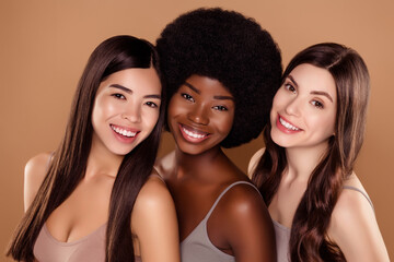 Photo of shiny charming three girlfriends wear crop tops smiling hugging isolated beige color background