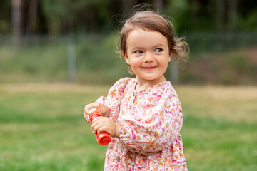 childhood, leisure and people concept - happy little baby girl with soap bubble blower in summer