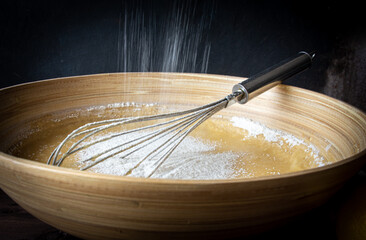 primer plano de varillas mezclando harina con huevo y azúcar