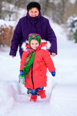 Grandmother and granddaughter walk on winter trails, bright and warm winter clothes, cold winter season.