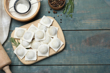 Homemade uncooked ravioli on blue wooden table, flat lay. Space for text