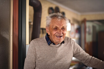 Portrait of elderly man standing indoors at home, laughing.