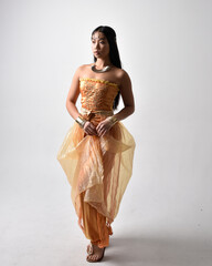 Full length portrait of pretty young asian woman wearing golden Arabian robes like a genie,...