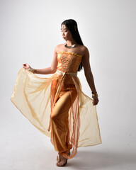 Full length portrait of pretty young asian woman wearing golden Arabian robes like a genie,...