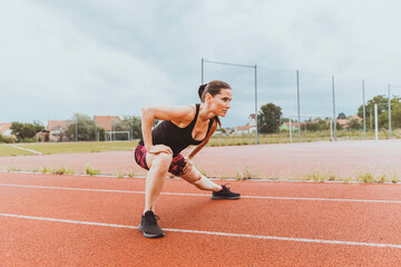 Female runner warms up on the running oval. Stretching