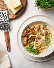 Italian cuisine. Pasta with chanterelles and parmesan cheese. Spaghetti with mushrooms and micro-greens. Pasta with cheese and vegetables. Italian dinner. Italian food on a gray background. - obrazy, fototapety, plakaty
