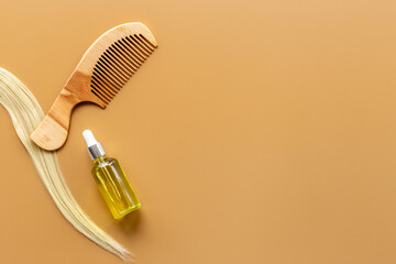 Hair essential oil with wooden comb and blond curl of hair