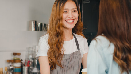 Woman barista, waitress showing gesture with menu and talking to customer at cafe restaurant. Beautiful young Korean girl order food across bar counter at coffee shop. Owner small business concept.