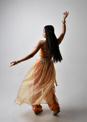 Full length portrait of pretty young asian woman wearing golden Arabian robes like a genie,...