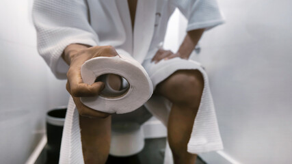 Selective focus of man hand with paper roll  which  he holds a roll of toilet paper Going to the...
