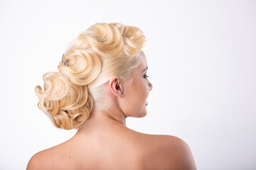 Portrait of a woman. Refined evening hairstyle. Bride. Styling. The girl stands with her back. Lock of hair. The hair is gathered and pinned up with a large barrette.