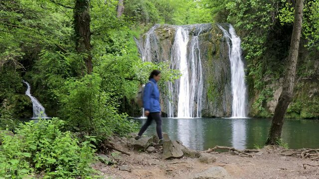 Tourist woman walking near beautiful waterfall in Spain, near from village Rupit in Catalonia
