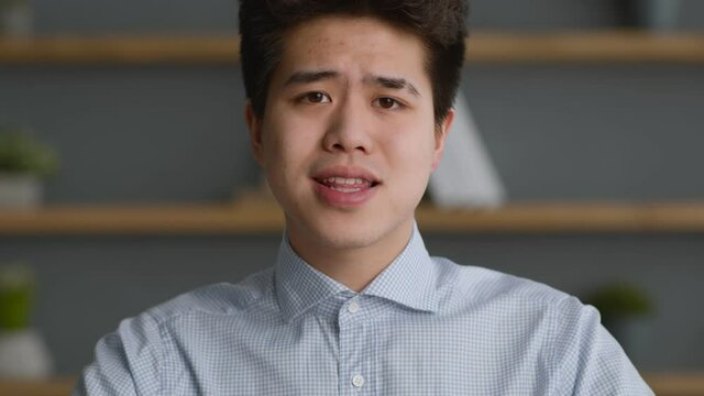 Webcam pov portrait of young confiden asian man talking to camera, conversating with coworkers or recording video blog
