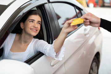 driver or customer paying with credit card to worker after refueling a vehicle at gas station