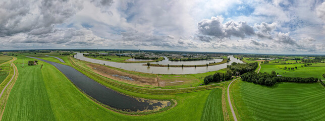 Dutch river IJssel landscape with floodplains and harbor in the background against a blue sky with...