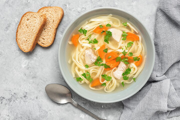 Chicken noodle soup close-up on gray grunge background. Top view, flat lay.