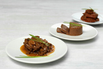Plates with different pet food and grass on white table. Space for text