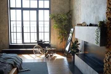 Wide angle image of empty wheelchair in modern apartment interior lit by sunlight, copy space
