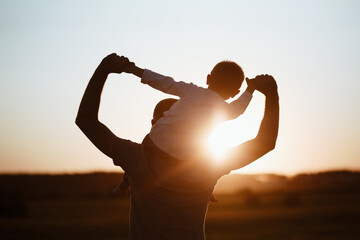 Father and son playing in the park at the sunset time. Family, trust, protecting, care, parenting,...