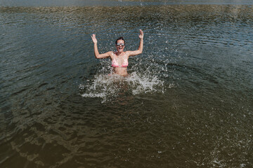 happy caucasian woman swimming in lake and splashing. summer time. fun outdoors