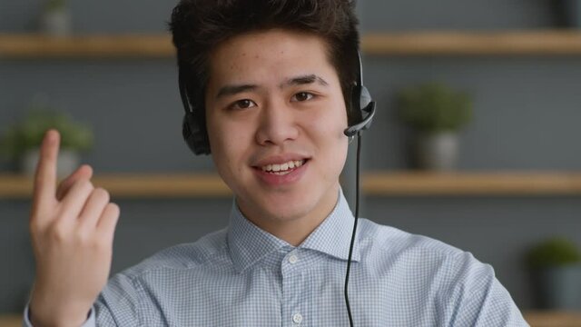 Portrait of young confident asian guy wearing headset talking to camera, explaining basics of online business