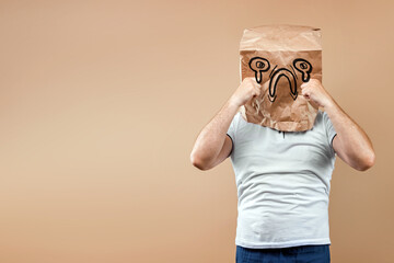 Men put a paper bag on their heads, on which a crying face, upset, bad mood is drawn. Isolated on...
