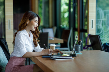 Asian Young Female using laptop computer at office. Student girl working at home. Work or study from home, freelance, business, lifestyle concept.