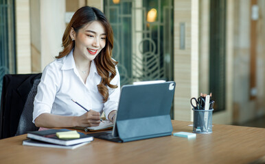 Asian Young Female using laptop computer at office. Student girl working at home. Work or study from home, freelance, business, lifestyle concept.